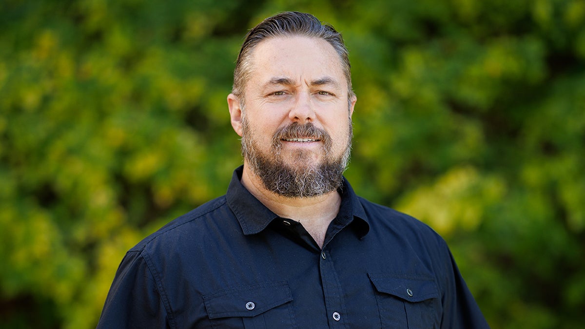 A portrait of Professor Michael Latner against Cal Poly foliage