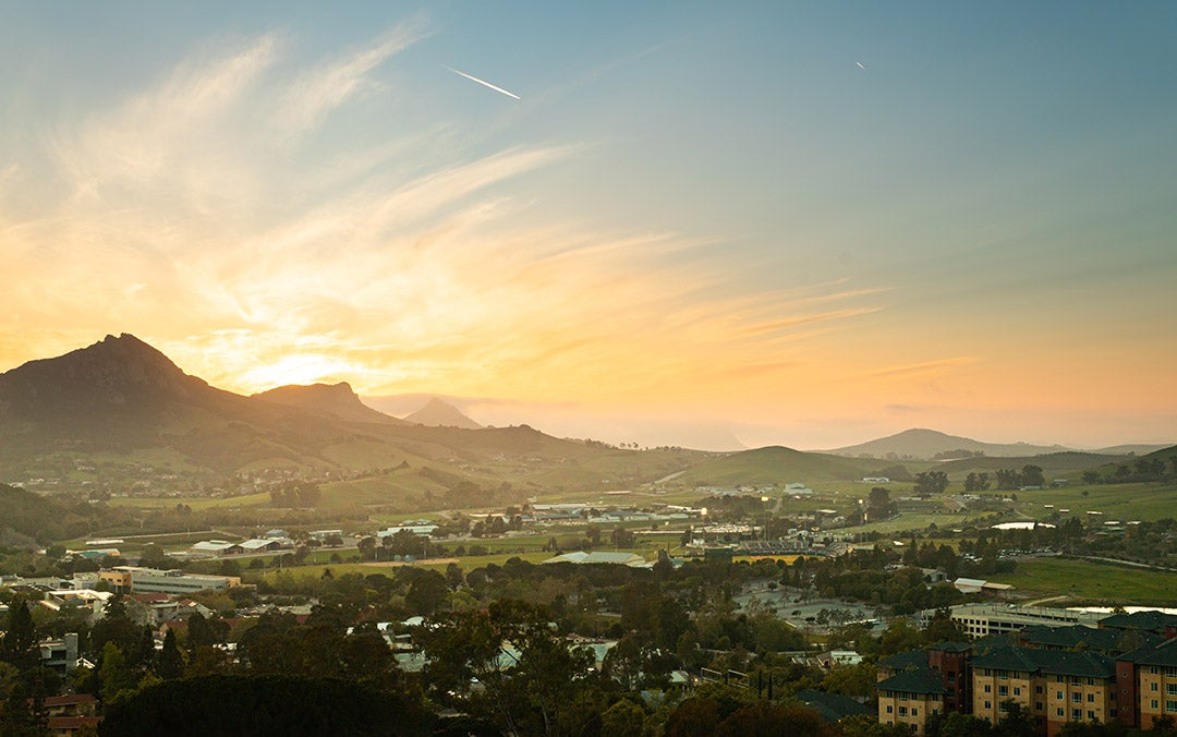 The sun sets behind the range of ancient volcanic cores called the cerros, seen from campus