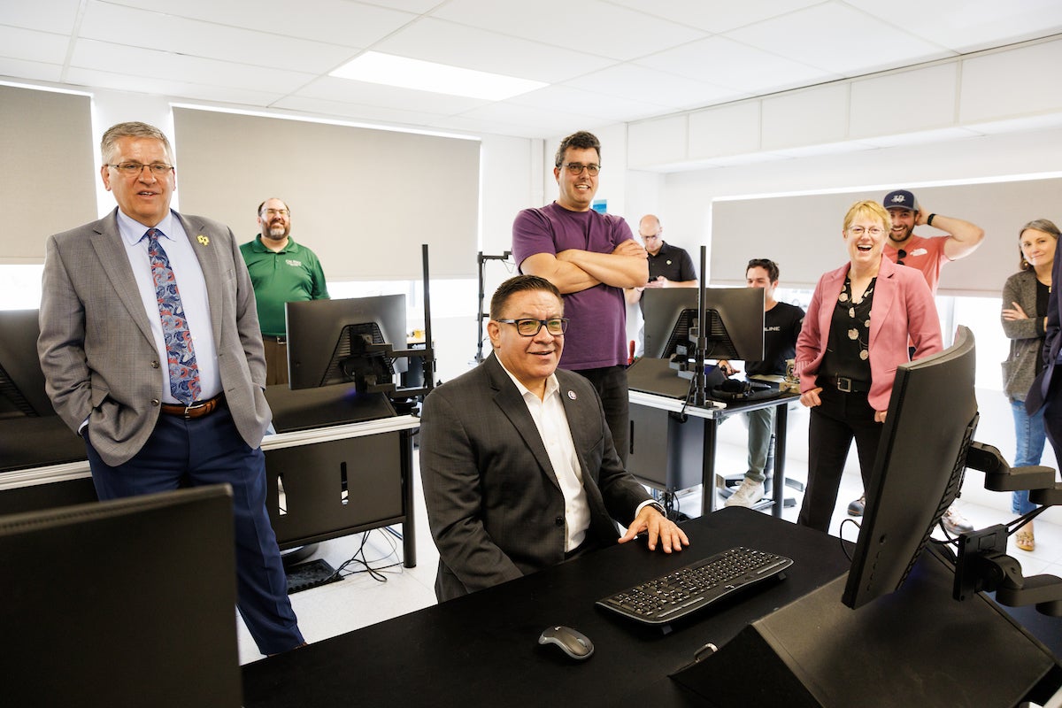 Congressman Carbajal and university leaders and other representatives in a computer room at the air hanger