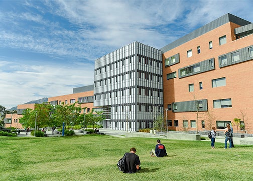 Students rest on the grass outside the Warren Baker Center for Science and Mathematics 