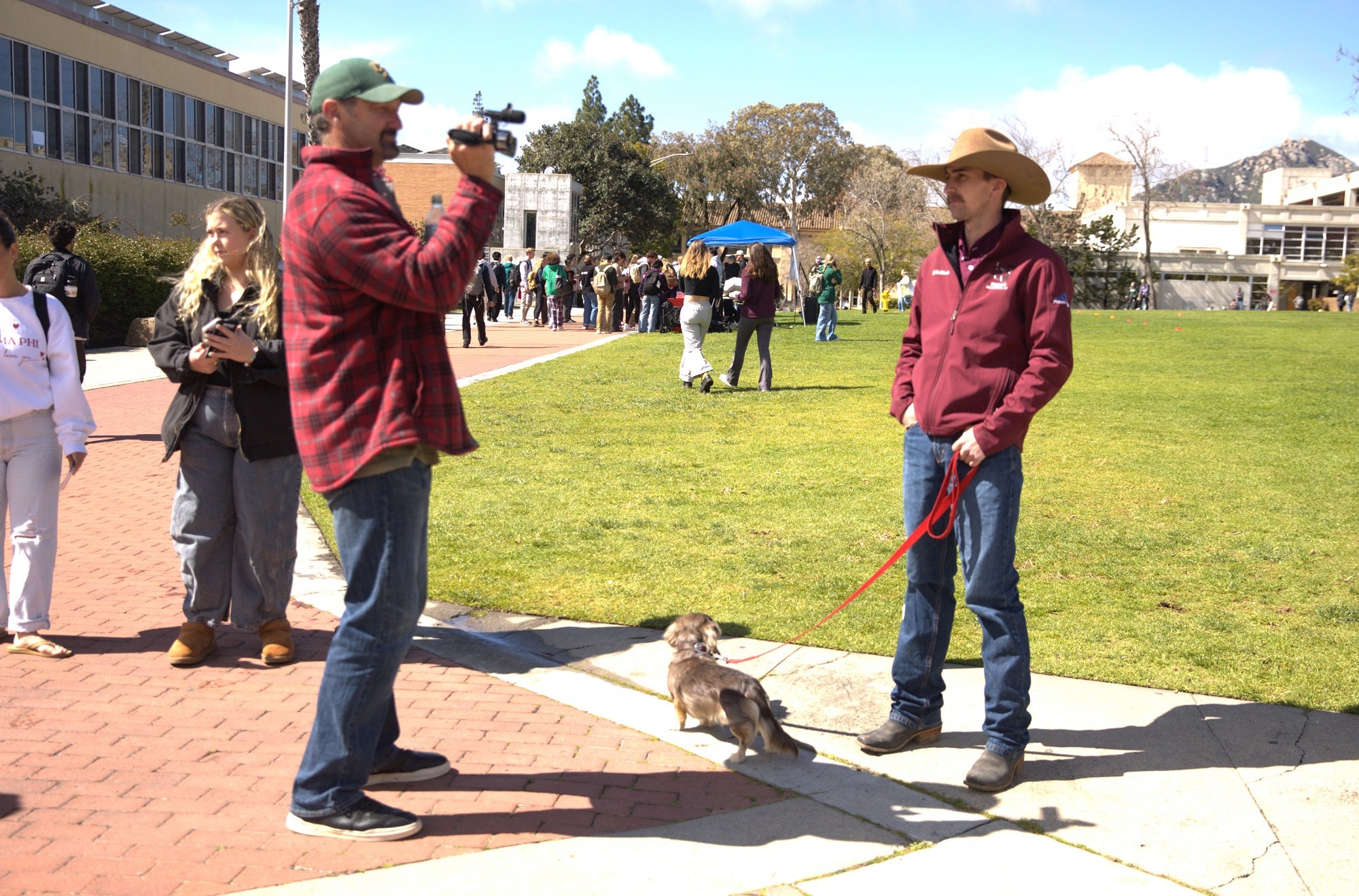 A student videographer films professional Cal Poly Rodeo saddle bronc rider Quintin McWhorter at a Dexter Lawn promotional event