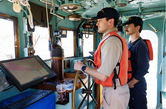 Two Cal Poly Maritime Academy cadets staff the Golden Bear's helm