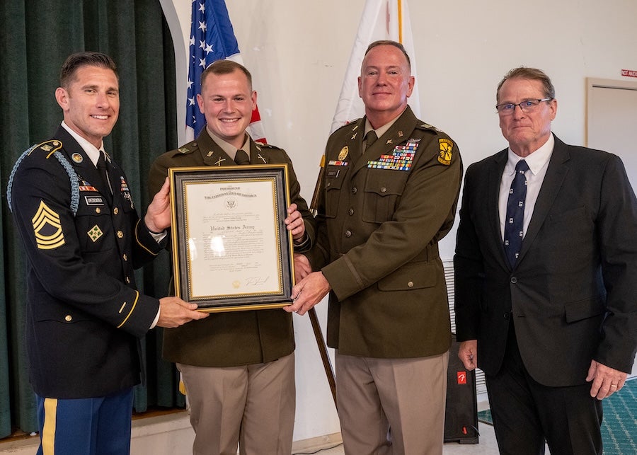 adet Andrew Koenig holds his Army commission while two Cal Poly ROTC officials and his father stand next to him