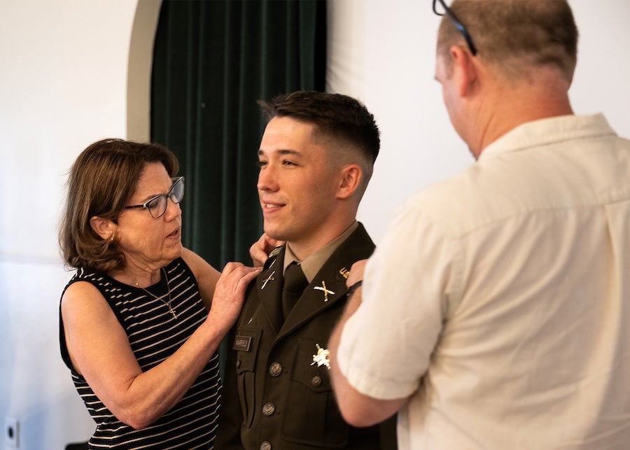 Cadet Nathaniel Warfield has his rank insignia pinned to his uniform by parents