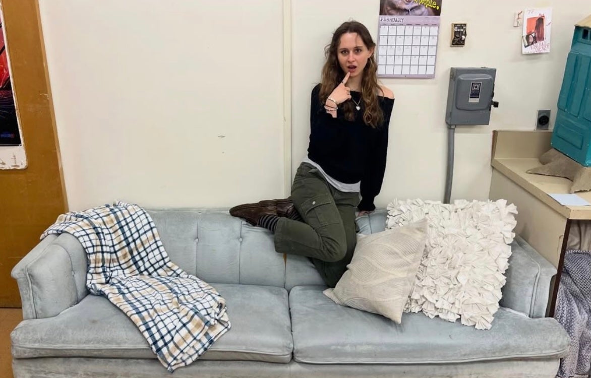 Artist Olivia Pye sits atop the art studio blue couch
