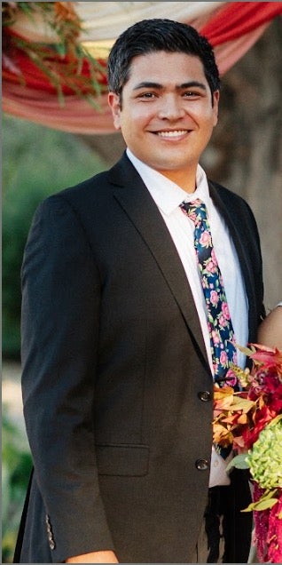 Cortland Rodriguez in suit and tie smiles at an event