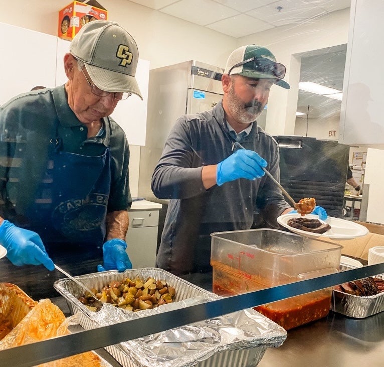 Richard Equinoa serves a meal alongside Russell Monteath during a community meal service at the Prado Day Center.