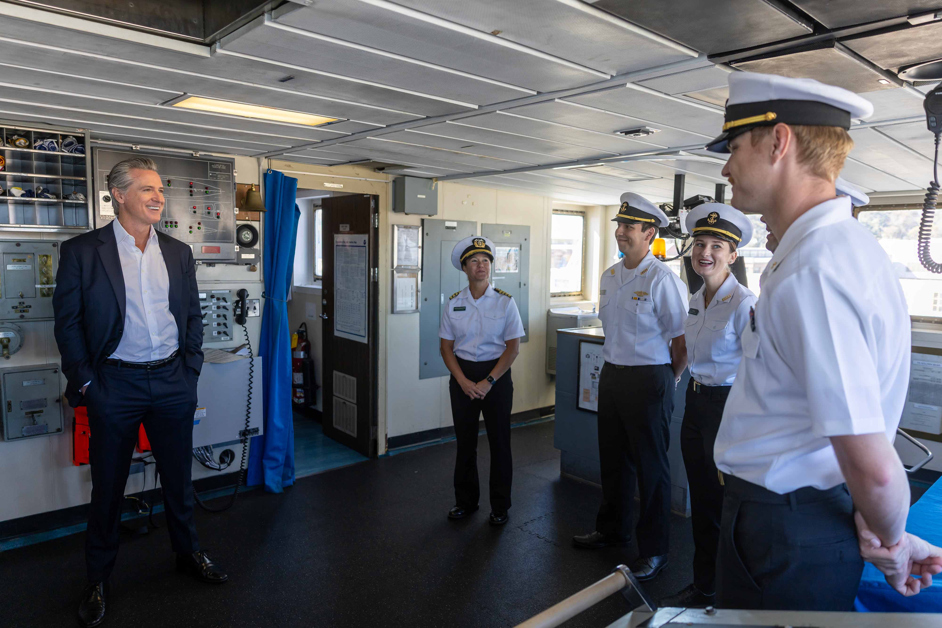 Gov. Gavin Newsom, left, and Capt. Samar Bannister with Cal Poly Maritime Academy speak with academy cadets aboard the Training Ship Golden Bear.
