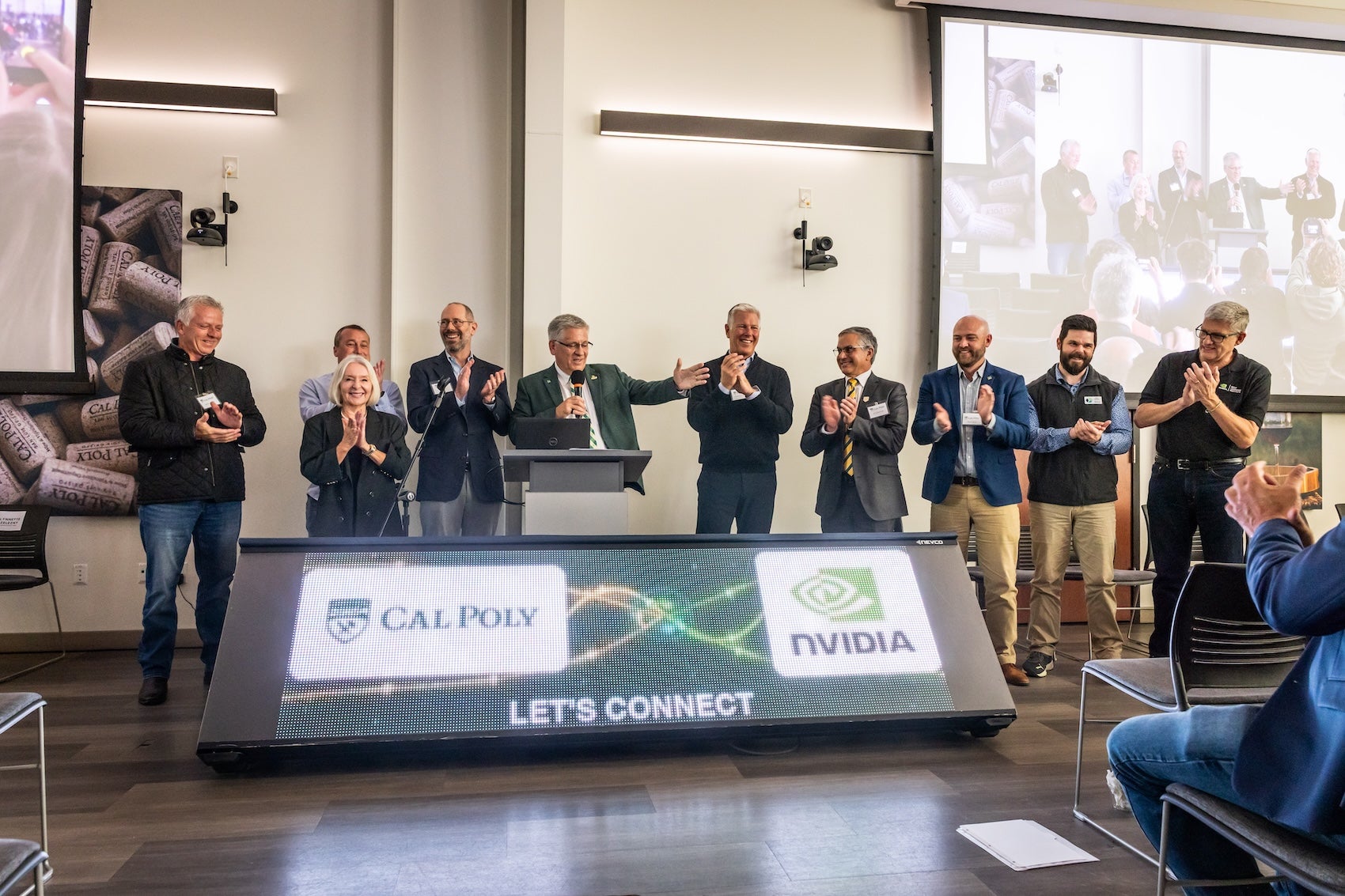 A group of people clapping behind a digital screen showing the Cal Poly and Nvidia logos