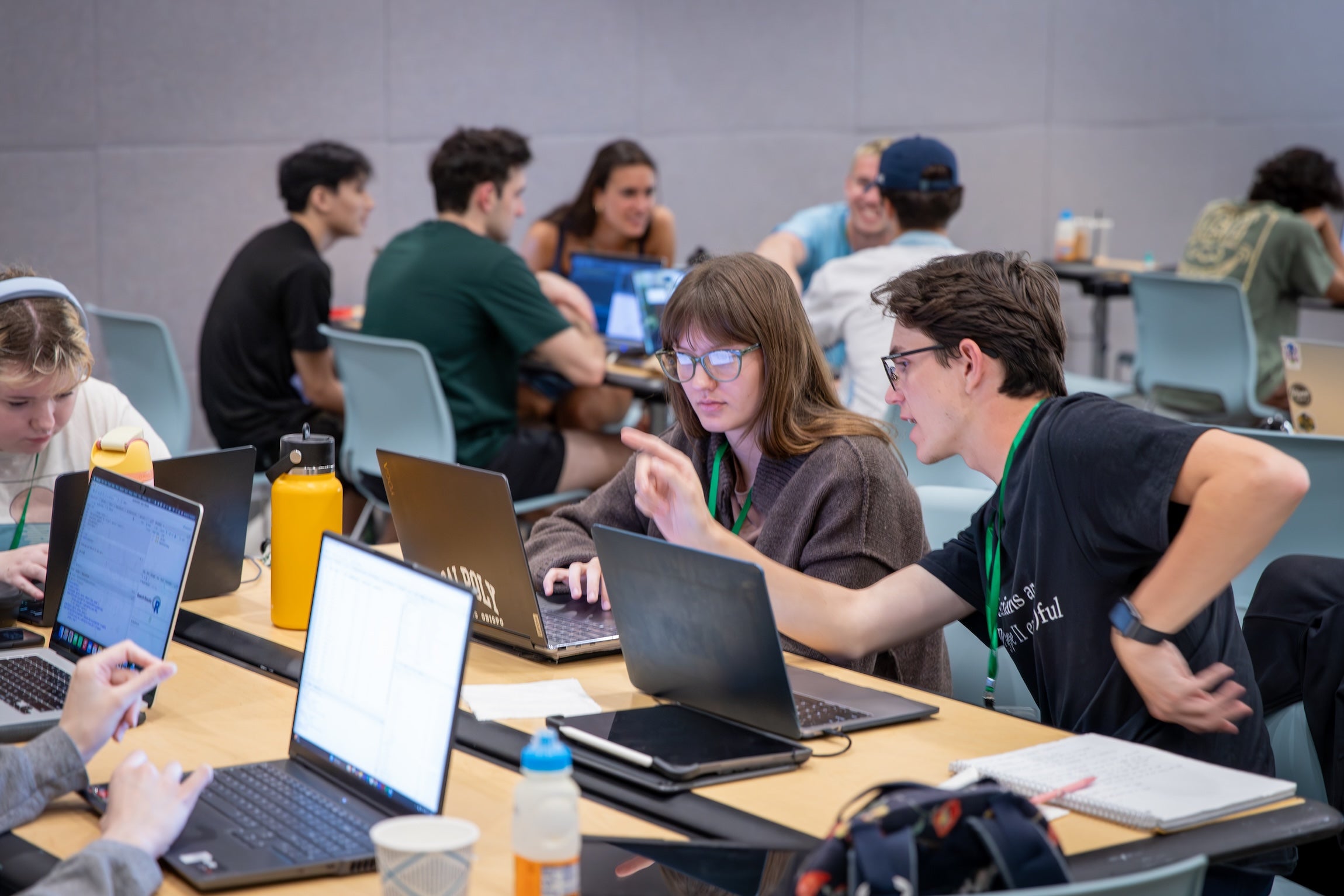Multiple students working on laptops in a classroom.
