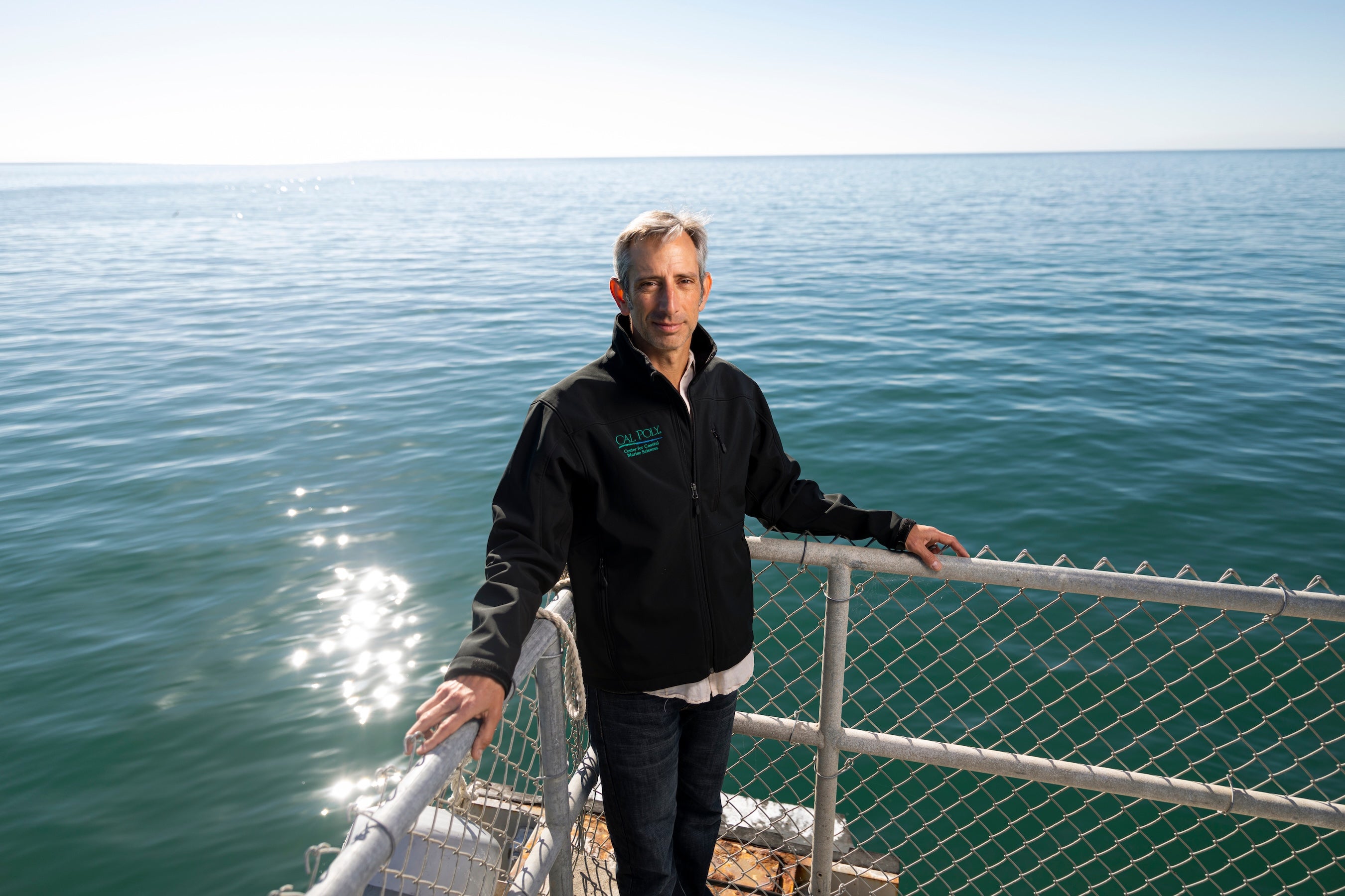 Ben Ruttenberg poses at the Cal Poly Pier with the ocean behind him
