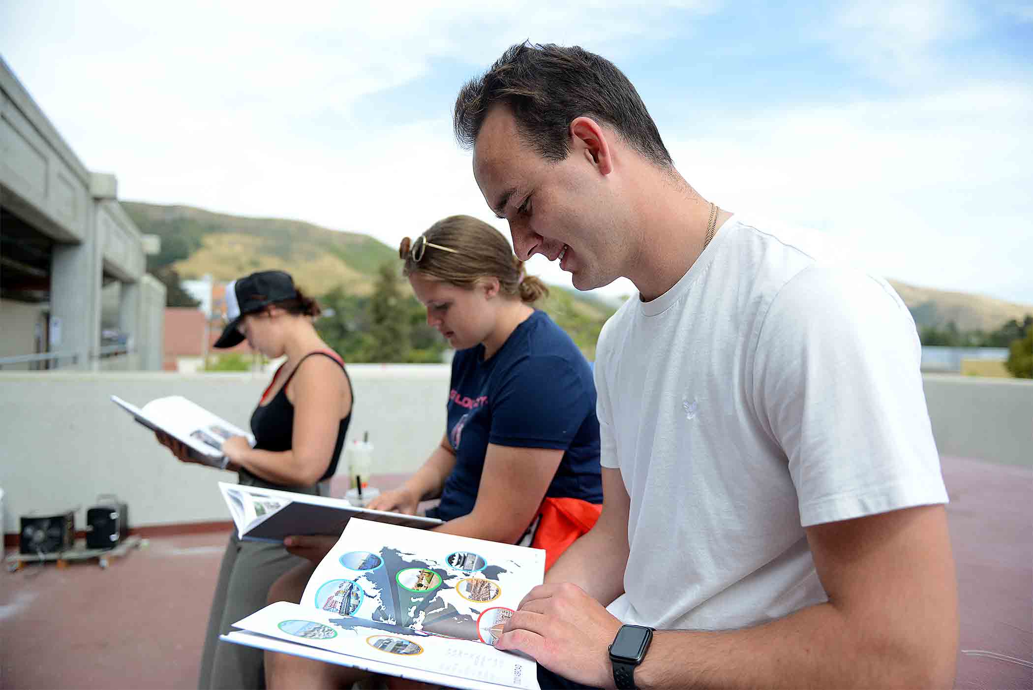 Three architecture students examine the yearbook while sunning themselves on the fourth-floor terrace of the Architecture building