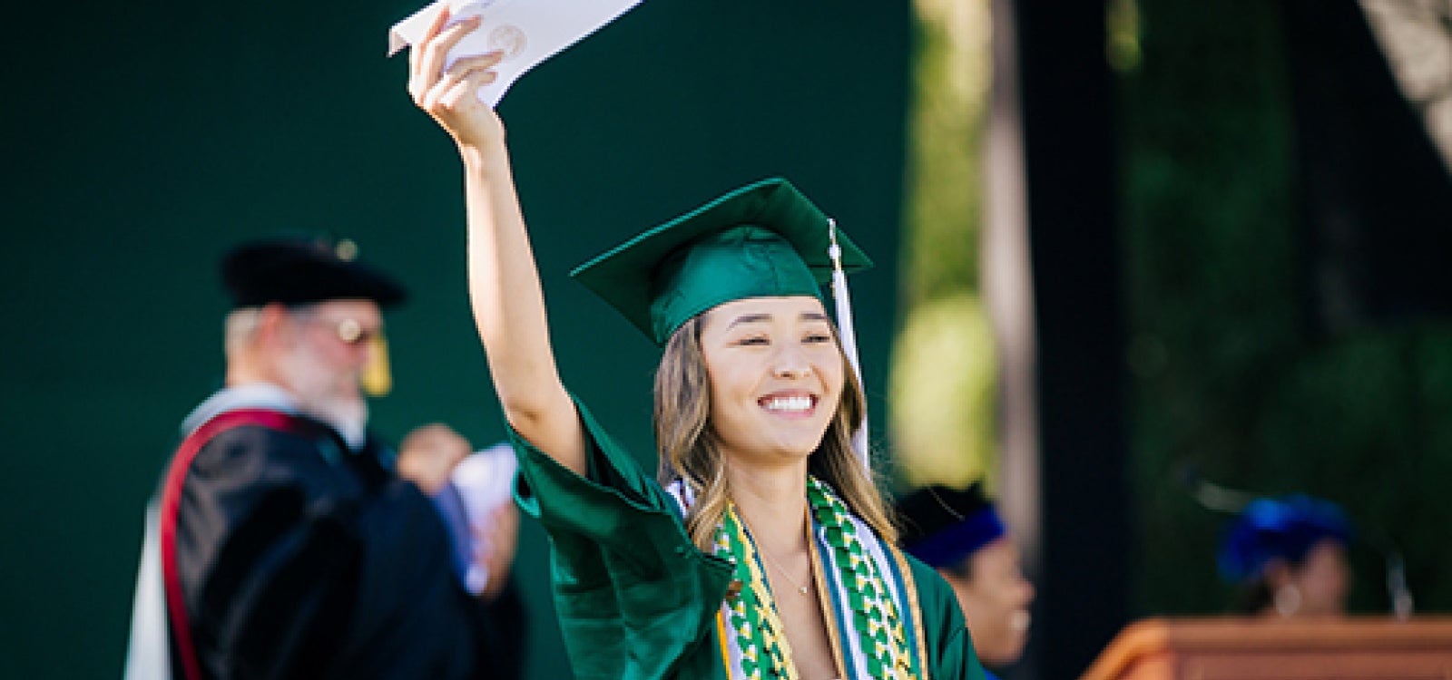 A 2023 College of Liberal Arts graduate waves to the crowd from the stage_photo by Joe Johnston