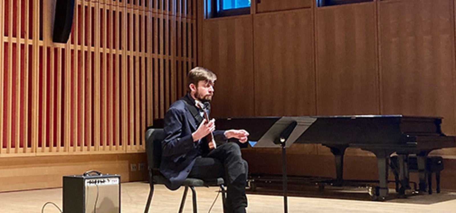 Guitarist Matt Sargent plays an electric guitar seated in front of a single amplifier speaker