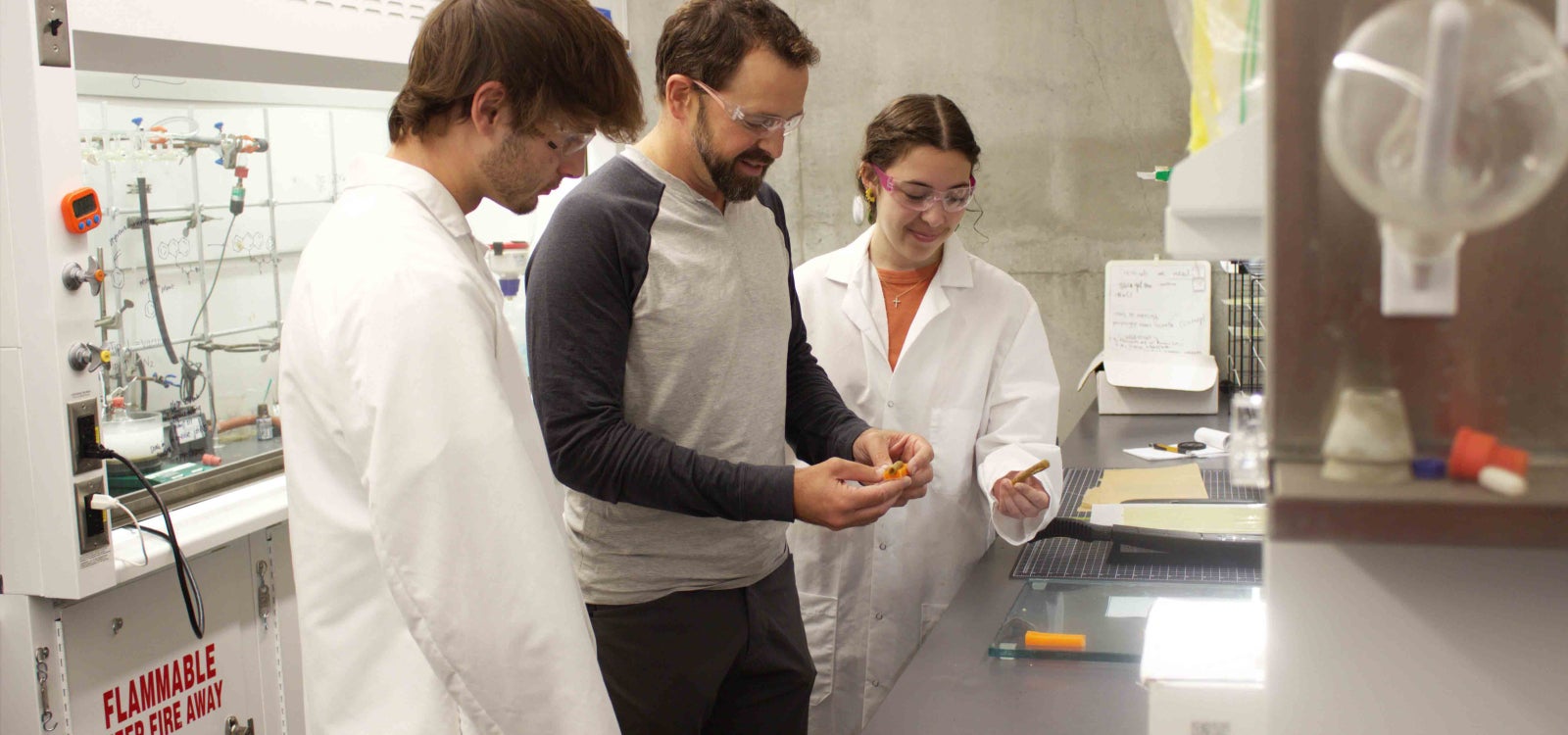 Cal Poly chemistry Professor Phil Costanzo works with two students in a college lab
