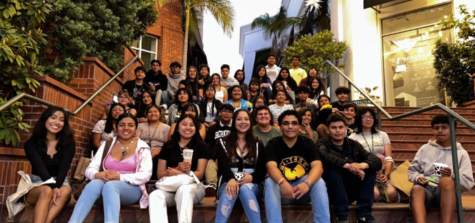 A group of Upward Bound high school students pose for a photo seated on the steps of a downtown San Luis Obispo shopping location