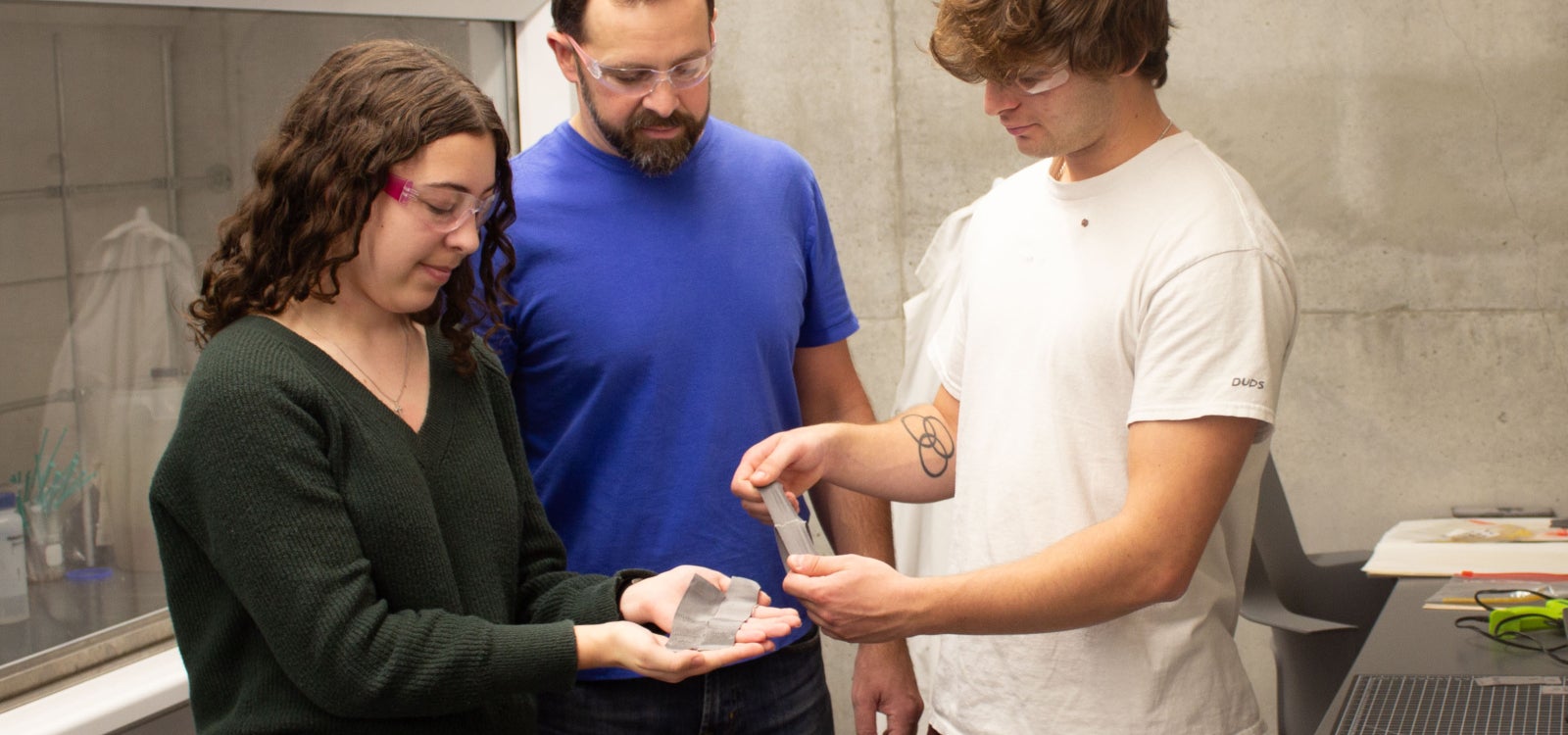 Chemistry Professor Phil Costanzo with Cal Poly students in a university lab discussing a D-glue product