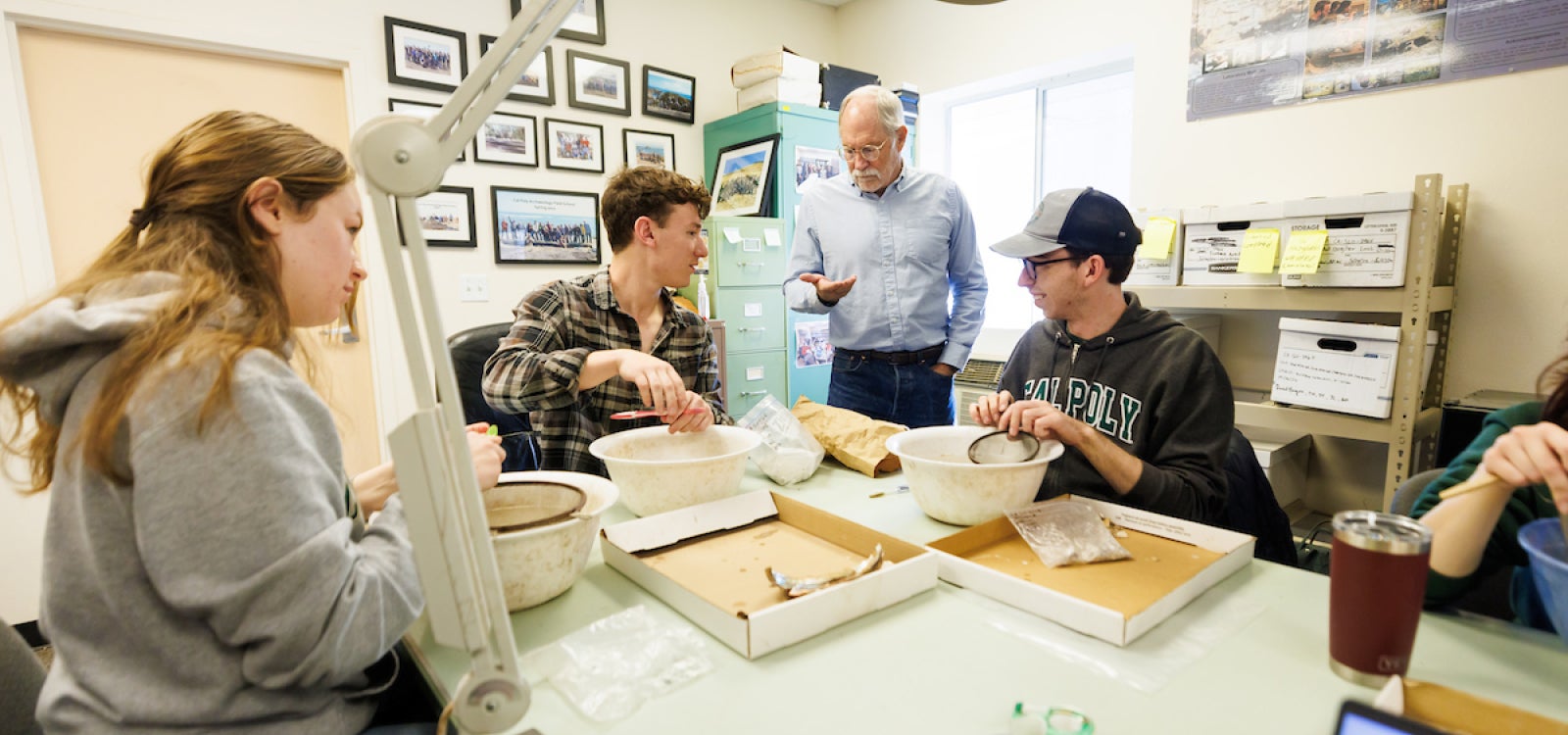 Students sit around a table cleaning unearthed Yoshida family artifacts 