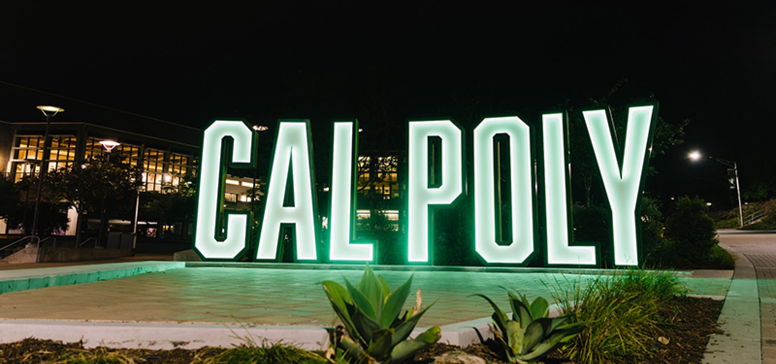 8-foot-tall letters spell out Cal Poly near the University Union  photographed at night 