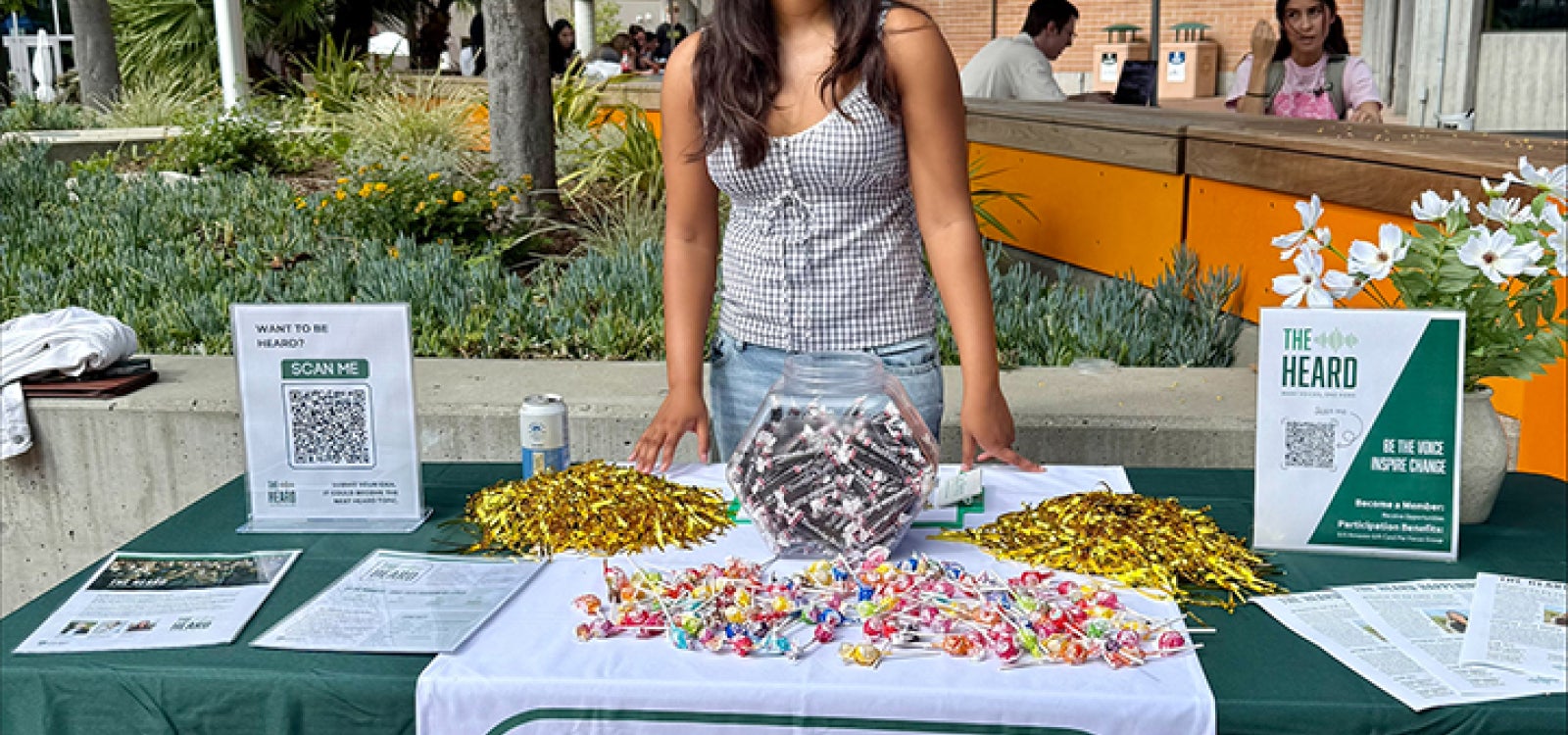 A HEARD Student stands at an information table in the University Union