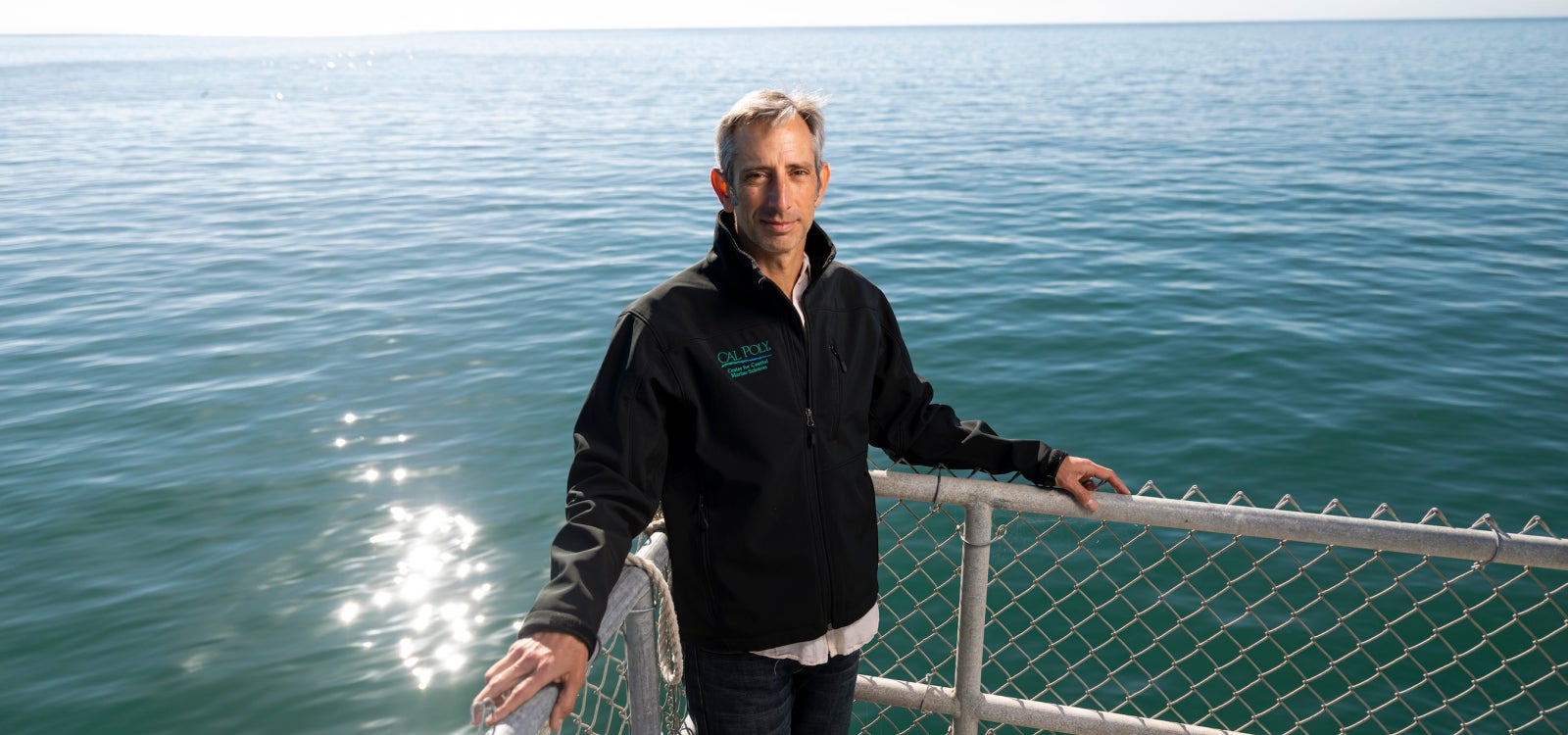 Ben Ruttenberg poses at the Cal Poly Pier with the ocean behind him