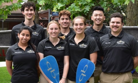 Seven members of the concrete canoe team pose together out of the water