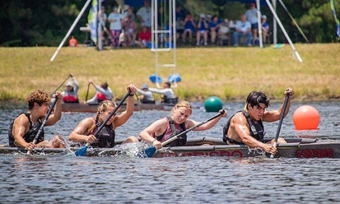 Four Cal Poly students paddle together in their concrete canoe