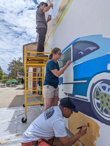 Three people painting the mural