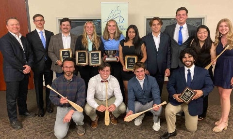 Cal Poly concrete canoe team pose with trophies including the silver national championship bowl