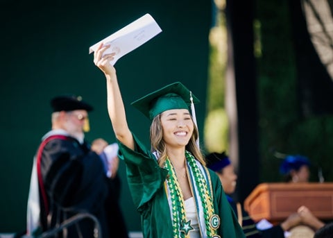 A 2023 College of Liberal Arts graduate waves to the crowd from the stage_photo by Joe Johnston