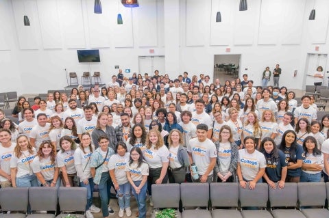 An auditorium filled with hundreds of students wearing #CaliforniansForAll College Corps T-shirts