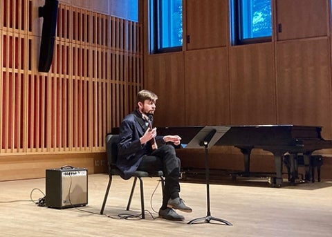 Guitarist Matt Sargent plays an electric guitar seated in front of a single amplifier speaker