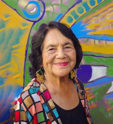 Dolores Huerta photographed in front of a colorful mural