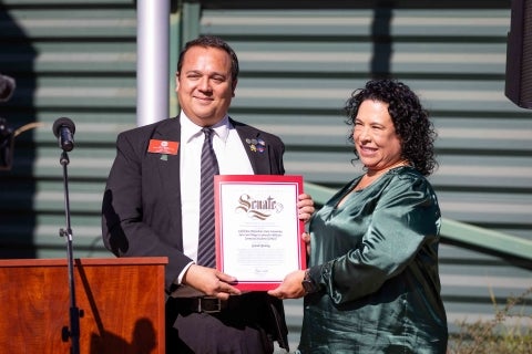 A representative of local state senator presents a resolution in support of the center to Lead Coordinator Kari Leslie 