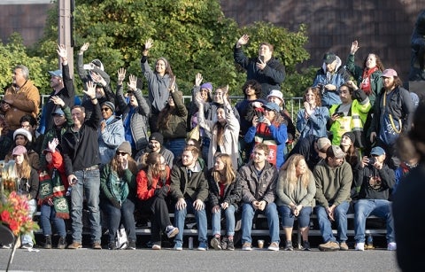 Students from Cal Poly universities cheer and wave to their float as it slowly heads ease on Colorado Boulevard