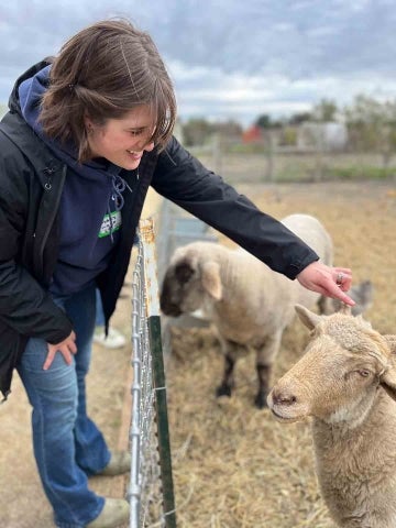 A woman student pats the head of a sheep