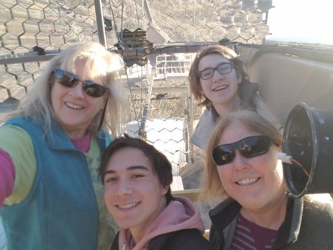 Three students and their faculty advisor stand in front of one of the VERITAS telescopes