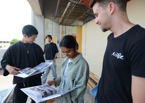 A group of four architecture students examine the yearbook during the first distribution day June 3