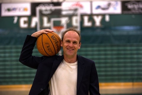 Professor Joseph Kuehn holds a basketball on the basketball court at Mott A thletic Center