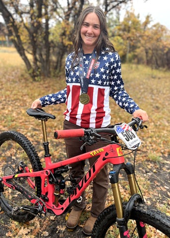 Mountain biker Gwen Ramsey in a racing jersy holding and her bicycle
