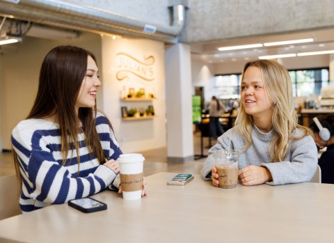 Two female students sit at a table in Julian's in Kennedy Library