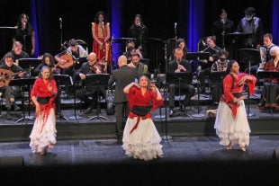 A trio of dancers in colorful costumes dance backed by the Cal Poly Arab Music Ensemble 