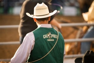 A Cal Poly Rodeo member wears a vest with the Cal Poly Rodeo name on the vest back