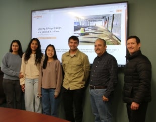 Four students, a faculty adviser and a project sponsor stand in front of a screen showing the JackRabbit website they helped refine.