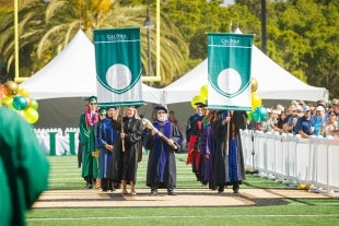 The podium part led by the campus mace heads for the commencement stage in June 2023