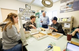 Students sit around a table cleaning unearthed Yoshida family artifacts 
