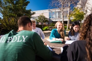 A group of five students study together at an outside table on the Cal Poly campus