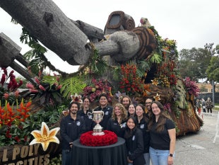 The executive team of Cal Poly Rose Float stand w the Sweepstakes Award in front of the Jungle Jumpstart float
