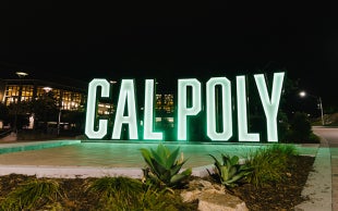 8-foot-tall letters spell out Cal Poly near the University Union  photographed at night 