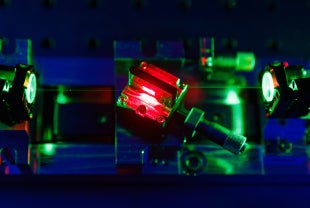 A green pump laser beam is directed into a crystal mounted inside a copper holder 